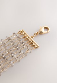 Gold-tone chain bracelet featuring layered strands of faceted clear crystals, with a lobster clasp and rectangular connector at the top.