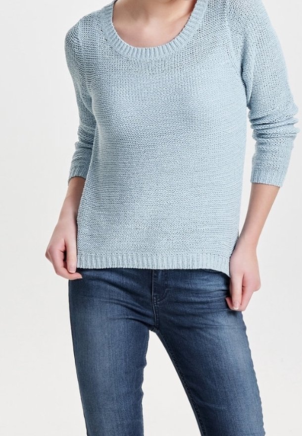 Hellblauer gestrickter Pullover mit Rundhalsausschnitt und langen Ärmeln, mit einem gerippten Saum. Kombination mit dunkelblauen Jeans.