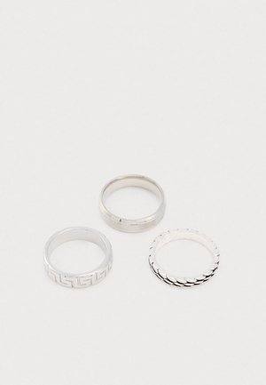 Három ezüst gyűrű. Az egyik geometrikus mintázatú, a második sima felületű, a harmadik pedig texturált, púpos mintázatú.