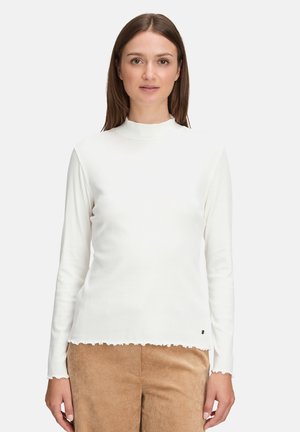 Witte lange mouw top met een opstaande kraag, geribbelde textuur en ruches aan de onderkant. Beschikt over een klein logo-accent aan de linkerkant onderaan.