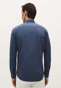 Marineblaue Langarmshirt mit einem klassischen Kragen. Verfügt über eine vordere Knopfverschluss und Manschetten, gefertigt aus glattem Stoff mit einem leichten Schimmer.