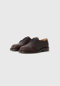 Zapatos oxford de cuero marrón con un acabado texturizado, diseño de cordones y punta redonda. Presenta un detalle de costura en contraste y suela de goma.