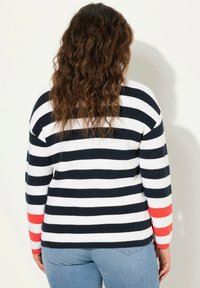 Gestreifter Pullover in Marineblau und Weiß mit oversize Passform. Mit roten Akzenten an den Ärmeln und gerippter Textur.