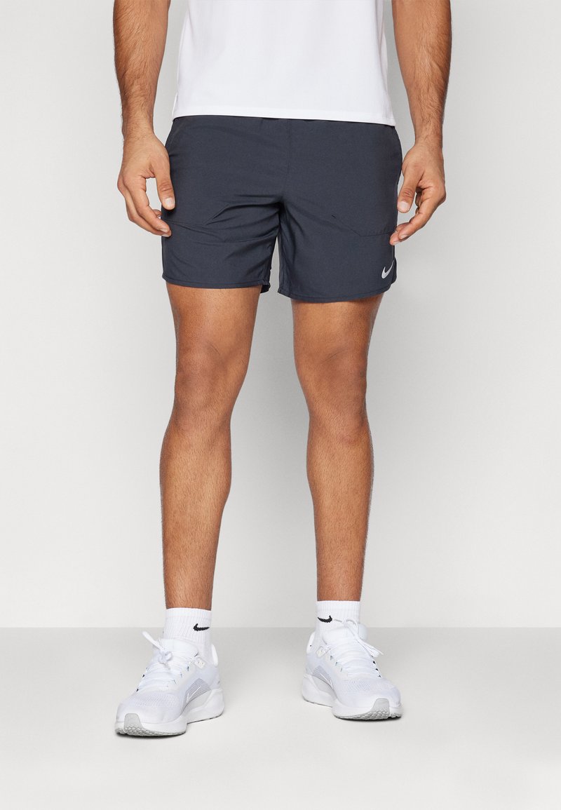 Shorts de sport bleu foncé avec deux poches latérales, une taille élastique et un petit logo Nike blanc sur la jambe gauche. Portés avec des baskets blanches.