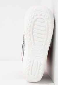 Semelle de basket blanche avec des motifs de rainures circulaires et ovales, montrant une texture et un design détaillés sur un fond blanc uni.