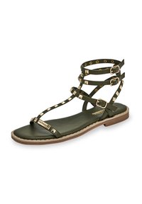 Grön lädersandal med flera vristband, pyramidformade nitar i guldton, platt sula och logotypdetalj på sidan.