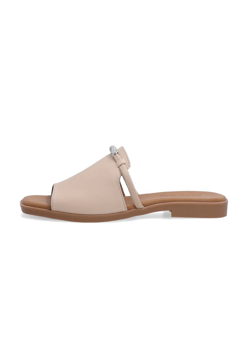 Beige læder slid sandal med en bred forreste rem, åben tå, slank side rem og en dekorativ sølvaccent. Flad brun sål.