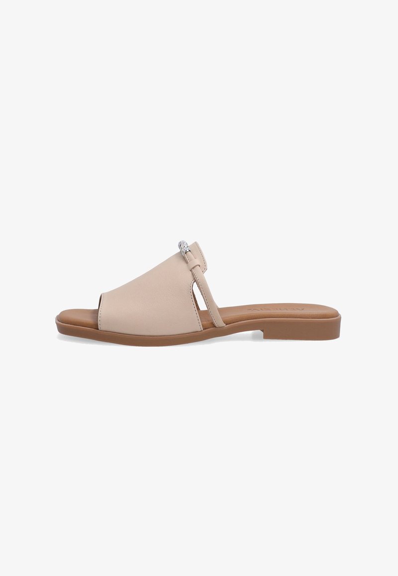 Beige læder slid sandal med en bred forreste rem, åben tå, slank side rem og en dekorativ sølvaccent. Flad brun sål.
