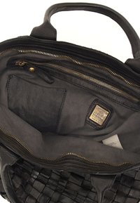 L'interno della borsa a tracolla in pelle nera presenta un design intrecciato, una cerniera dorata, molteplici tasche e foderatura in tessuto. I dettagli dell'etichetta sono visibili all'interno.