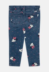Pantalones de mezclilla con cinturilla elástica, que presentan un patrón de lunares y estampados de un personaje con un lazo sobre un fondo azul oscuro.