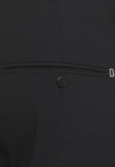 Tessuto nero con una finitura texture, dotato di un'apertura per tasca orizzontale e un dettaglio a pulsante nell'angolo inferiore destro.