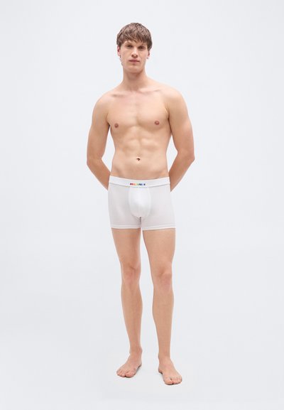 Boxer blanc en tissu extensible, avec une ceinture logo ornée d'accents arc-en-ciel, et une coupe ajustée. Texture lisse et légère.
