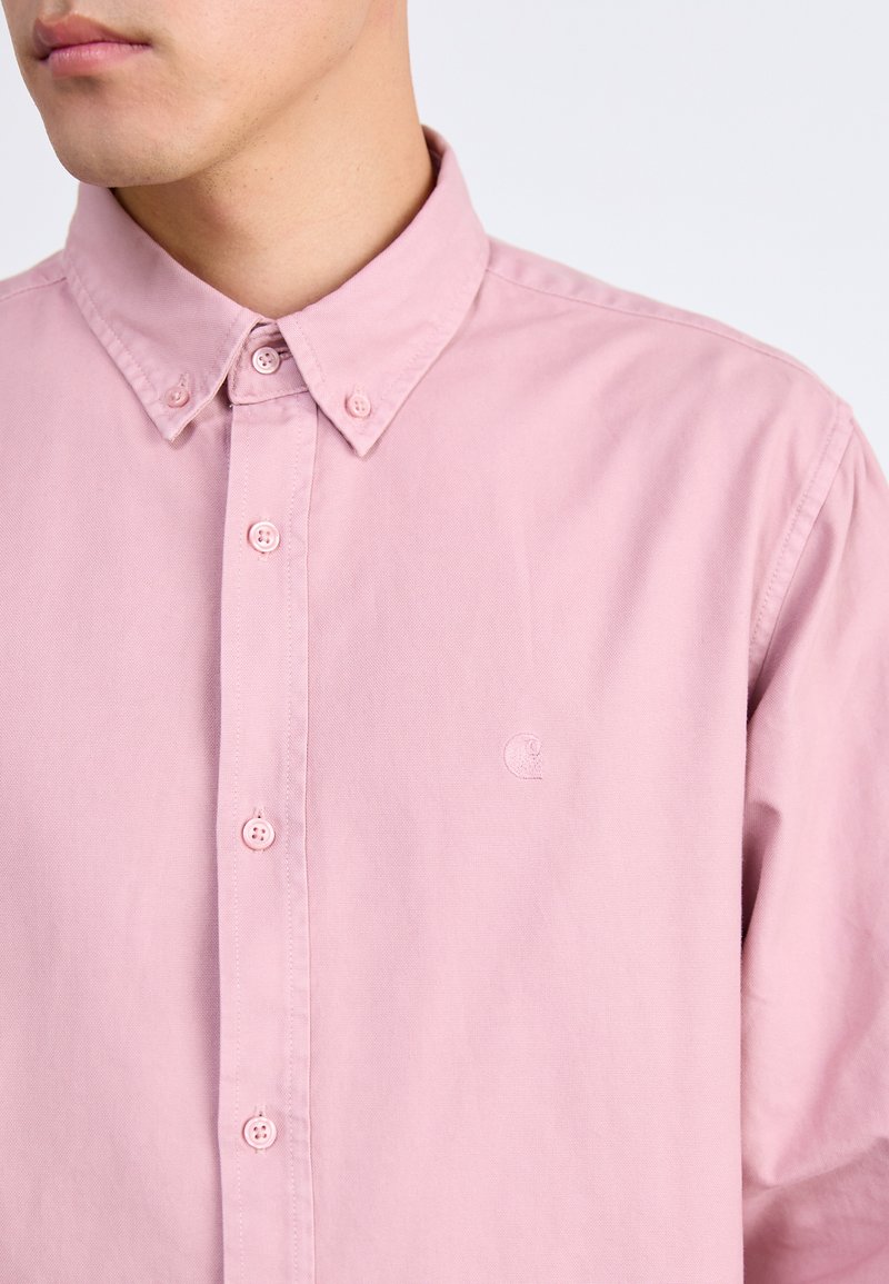 Camicia button-up rosa chiaro in cotone con colletto a punta, dotata di bottoni coordinati e un logo discreto sul petto.