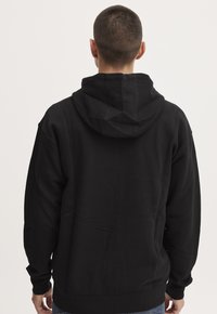 Zwarte hoodie met een eenvoudig ontwerp. Bevat een kangoeroezak, ribgebreide manchetten en zoom, gemaakt van zacht katoen.