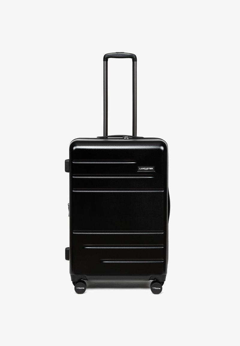 Valise rigide noire avec poignée télescopique et quatre roues, de marque Lancaster, debout sur un fond blanc.