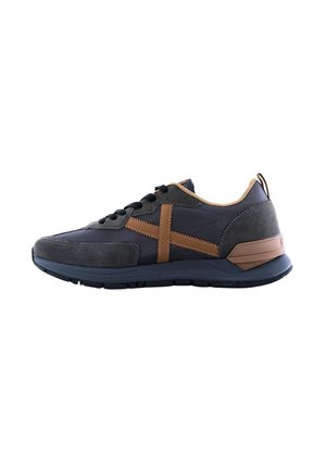 Zapatillas con parte superior azul marino y acentos de ante gris, rayas de cuero marrón y suela de goma texturizada. Diseño con cordones y un lazo en la parte trasera.