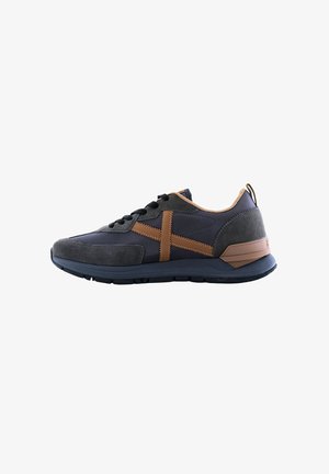 Zapatillas con parte superior azul marino y acentos de ante gris, rayas de cuero marrón y suela de goma texturizada. Diseño con cordones y un lazo en la parte trasera.