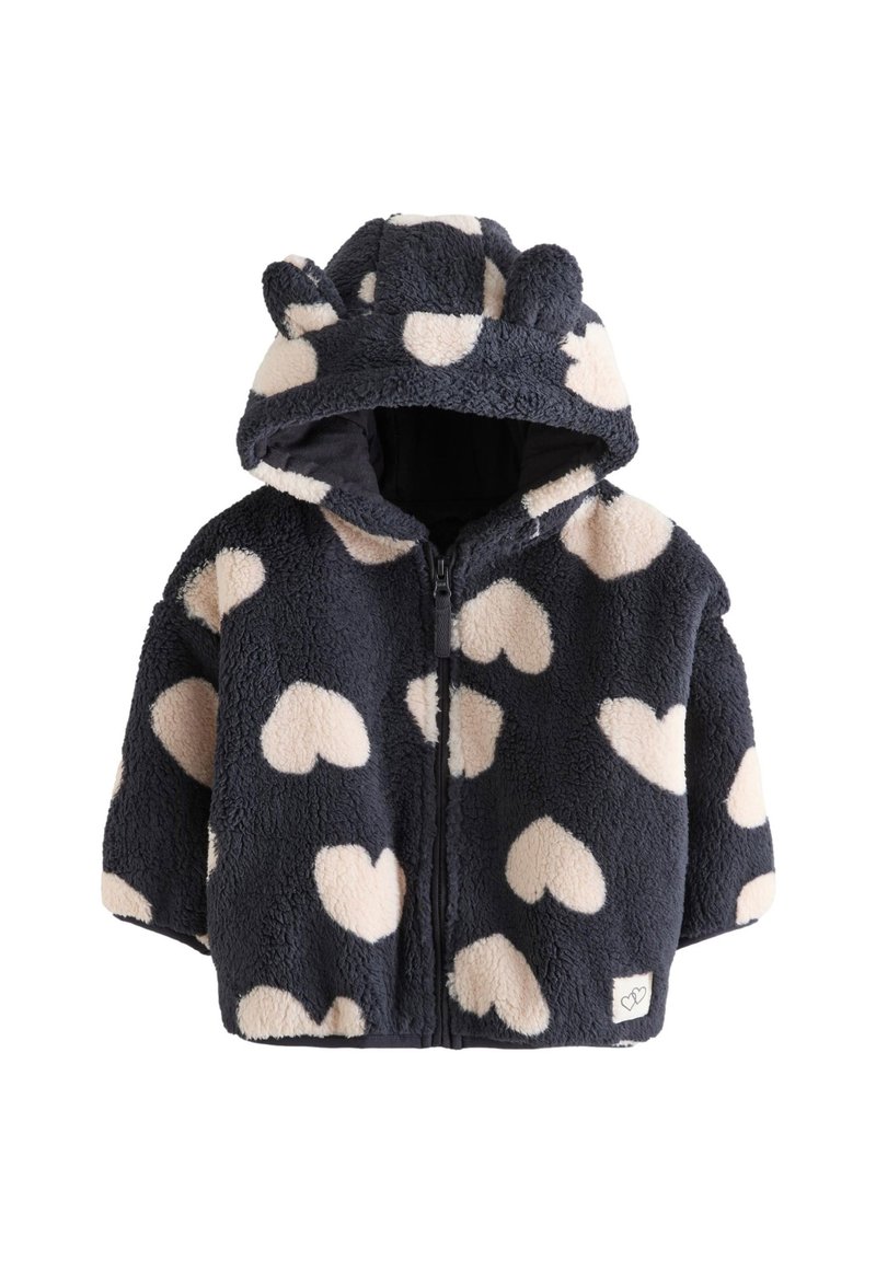 Veste en polaire bleue marine avec des motifs de cœurs crème, capuche avec oreilles d'ours, fermeture éclair à l'avant et texture douce. Comprend une petite étiquette logo à l'ourlet.