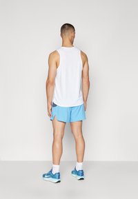 White sleeveless shirt and light blue athletic shorts. Blue running shoes with white accents. Clean background, no additional details.