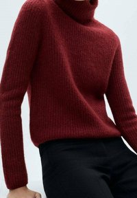 Rode, textuurgebroken turtleneck trui met een geribbeld patroon en lange mouwen, gecombineerd met donkere broeken. De nadruk ligt op het gezellige materiaal en een snug fit.