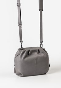 Gray leather crossbody bag with gathered detailing, a zip closure, and adjustable strap. Smooth texture and rounded shape.