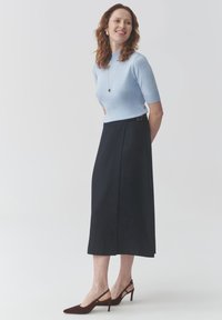 Light blue fitted top with short sleeves paired with a dark blue knee-length skirt. Brown pointed-toe heels complete the outfit.