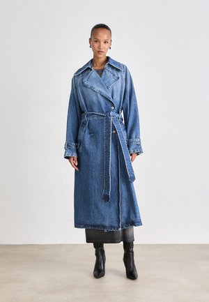 Cappotto lungo in denim azzurro chiaro, con design doppiopetto, colletto ampio, cintura in vita e tasche laterali. Texture liscia e lunghezza al ginocchio.