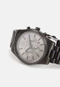 Montre chronographe en acier inoxydable noir avec des accents argentés, un boîtier rond et trois sous-cadrans sur un cadran gris. Fenêtre de date à 4 heures.