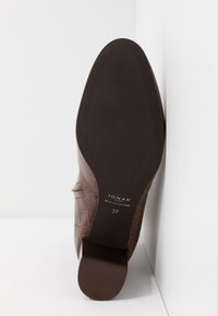 Semelle de chaussure en cuir marron avec marque Jonak, fabriquée au Portugal, pointure 37, présentée debout sur un fond blanc en coin.