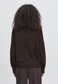 Maglione marrone a maglia con una vestibilità rilassata, spalle cadenti e orlo a coste. Texture morbida, design semplice e maniche di lunghezza intermedia.