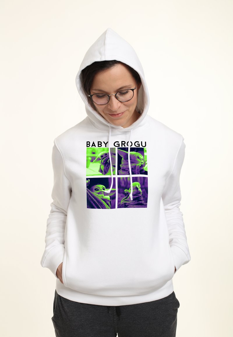 Hoodie blanche avec un graphique sur le devant représentant quatre panneaux verts et violets d'un personnage, étiqueté "BABY GROGU" en texte noir gras.