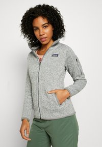Grauer Fleecejacke mit hohem Kragen, Reißverschluss und Seitentaschen. Verfügt über kontrastierende graue Besätze und ein kleines Logo auf der linken Brust.