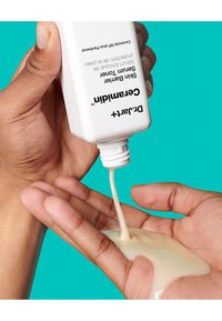 Bouteille en plastique blanche pressée, déversant une lotion crémeuse de couleur beige clair sur une main brune. L'arrière-plan est d'un bleu turquoise vif.