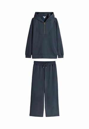 Navy blue hoodie with half-zip, oversized fit, and kangaroo pocket, paired with matching wide-leg pants featuring an elastic waistband.