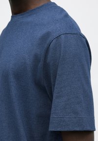 T-shirt en coton bleu foncé à manches courtes, col rond et texture douce. Présente un motif chiné subtil et des détails de couture soignés.