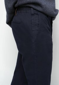 Pantalons bleu marine avec une finition texturée, présentant des poches latérales et une taille élastique pour plus de confort. Le tissu semble durable et flexible.