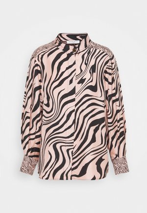 Chemise à manches longues avec des rayures ondulées zébrées roses et noires, col montant et poignets boutonnés sur un fond uni.