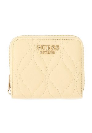 Petit portefeuille beige zippé avec surpiqûres matelassées, logo doré "GUESS EST 1981" et coins arrondis sur fond blanc.