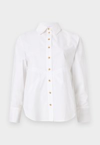 Chemise blanche à manches longues avec un col pointu et des boutons marron clair au centre devant.