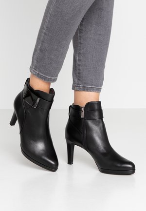 Black leather ankle boots with a pointed toe and 8 cm heel, featuring a glossy cuff accent and side zipper closure. Textured finish.