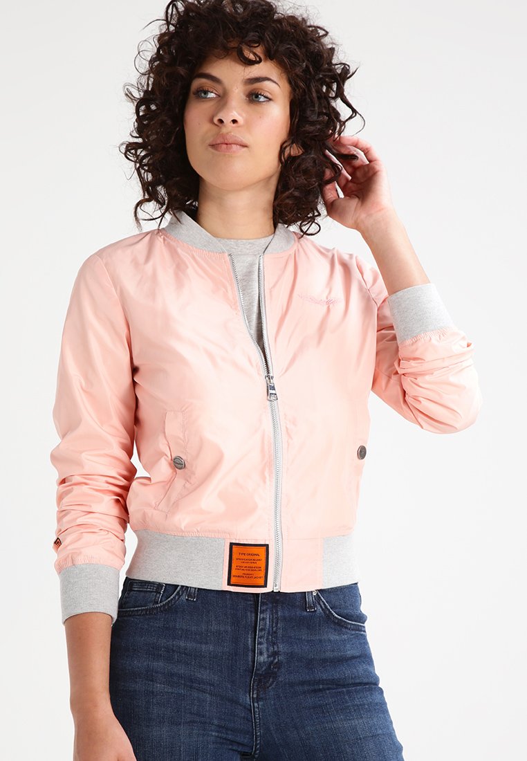 Giacca bomber rosa con chiusura a zip frontale, polsini grigi a coste e un'etichetta arancione in vita; texture lucida e design aderente.