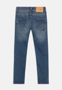 Jeans de mezclilla azul oscuro con un diseño ajustado. Presentan dos bolsillos traseros, una etiqueta de cuero en la cinturilla y una textura ligeramente desgastada.