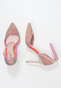 Beige high-heeled shoes with a pointed toe, featuring cut-out patterns, a pink accent on the edges, and an orange inner lining.