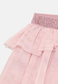 Jupe en tulle rose clair avec des volants superposés, dotée d'une ceinture pailletée rose. Le tissu est doux et transparent, offrant une apparence délicate.
