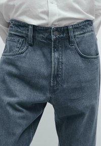 Mørkeblå denimjeans med et klassisk fem-lomme design, der har en knaplukning, robust talje og en let falmet tekstur.