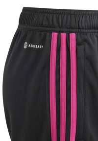 Schwarze Sportshorts mit einem breiten elastischen Bund und drei vertikalen pinken Streifen an der Seite. Mit AEROREADY Logo-Detail.