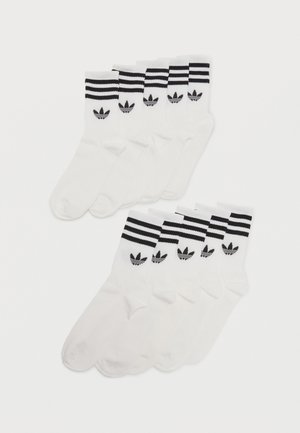 Dieci calzini bianchi a taglio basso con il logo a trifoglio Adidas nero e due strisce nere sulla parte superiore, disposti in due file sovrapposte.