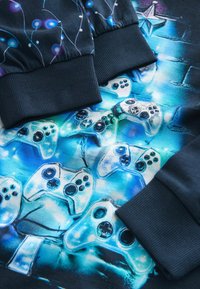 Black sweatshirt featuring a vibrant blue graphic of video game controllers. Ribbed cuffs with colorful light patterns. Smooth texture.