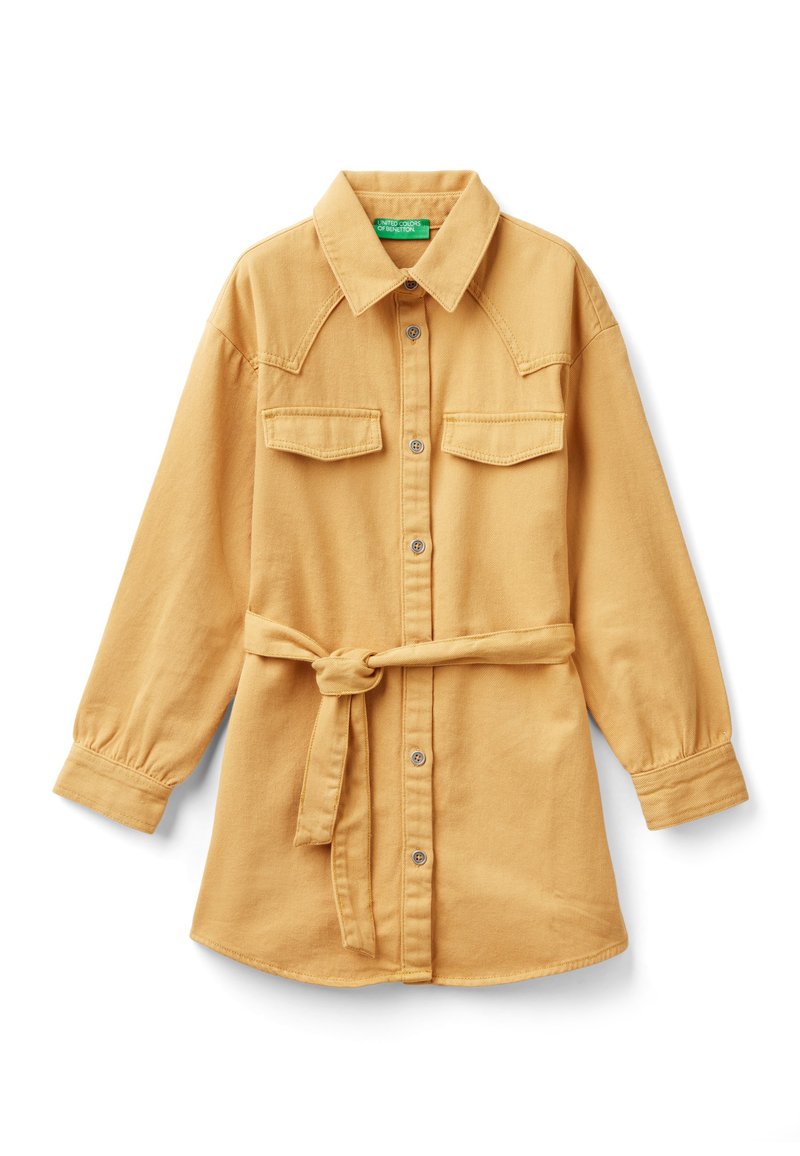 Robe chemise en denim de coton jaune moutarde, avec un boutonnage sur le devant, deux poches poitrine et une ceinture en tissu à la taille. Manches longues.