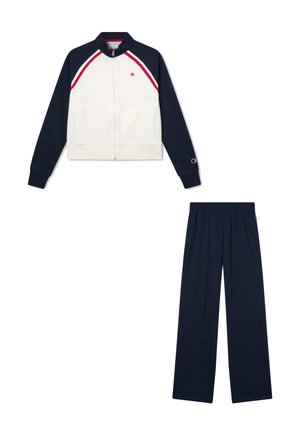 Giacca da pista bianca e blu navy con zip e strisce rosse abbinata a pantaloni da pista blu navy con elastico in vita.